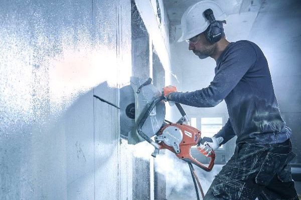 Concrete wall being cut, dust flying off the blade